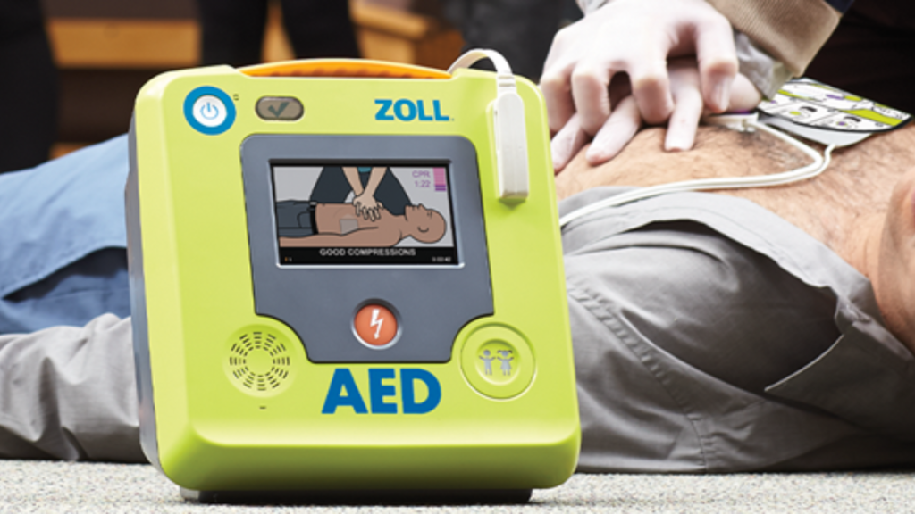 DEA Zoll Medical indicando compresiones más fuertes. En el fondo se ve persona recibiendo RCP
