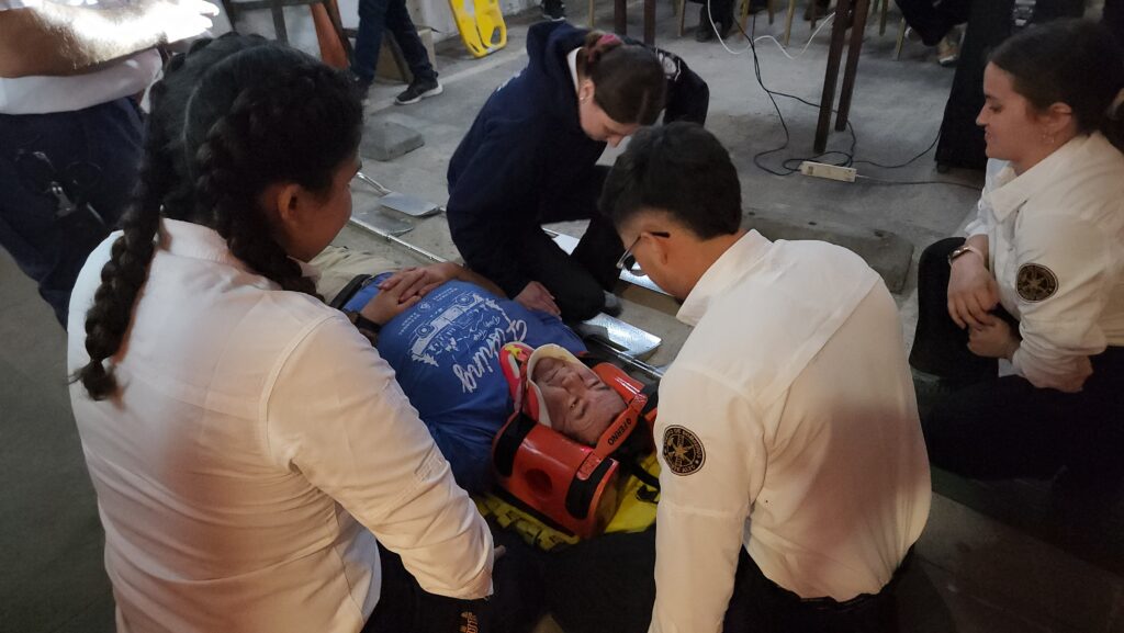 Voluntarios de bomberos practicando restricción de movimiento espinal